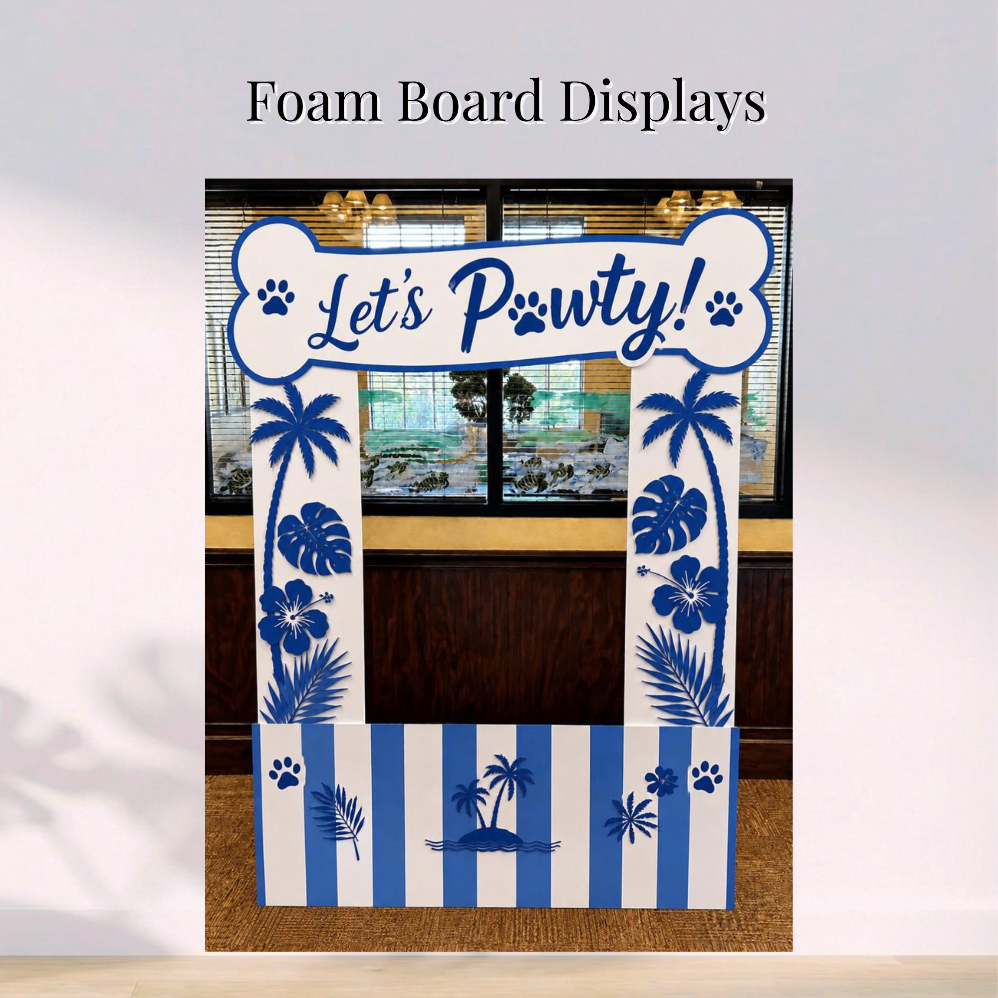 Blue and white dog-themed foam board display with a “Let’s Pawty” bone-shaped header and tropical decorations