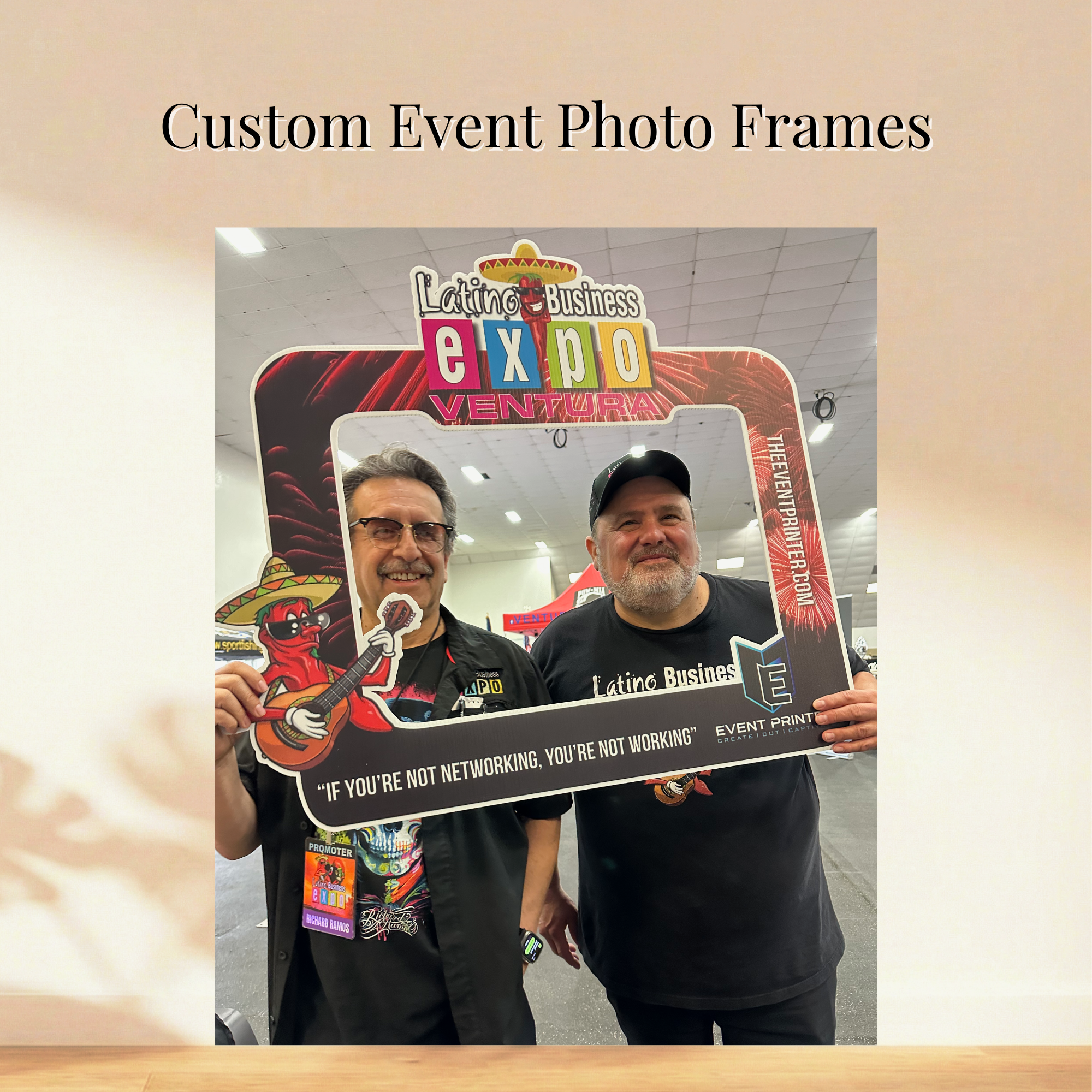 Two attendees holding a branded Latino Business Expo Ventura selfie frame
