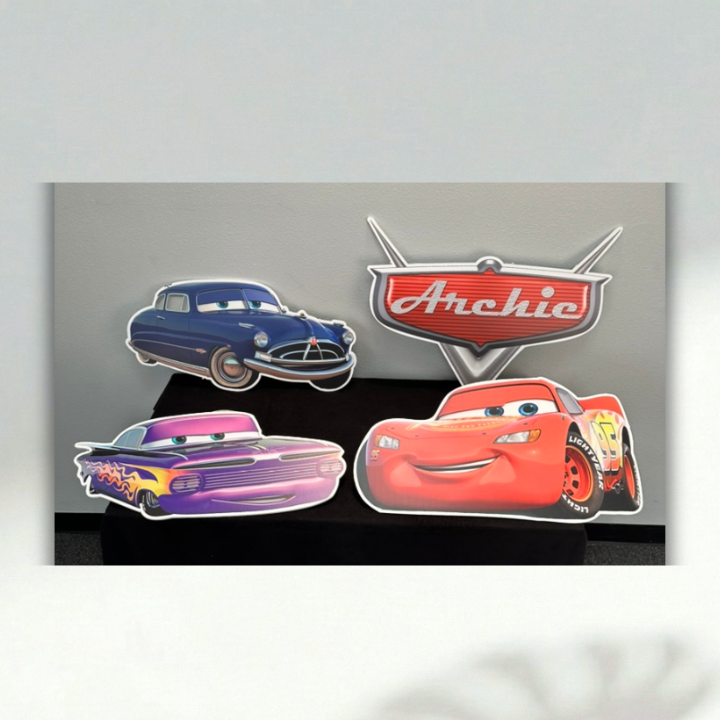 Cars birthday character cutouts featuring Lightning McQueen, Doc Hudson and Ramone with a personalized Archie sign.