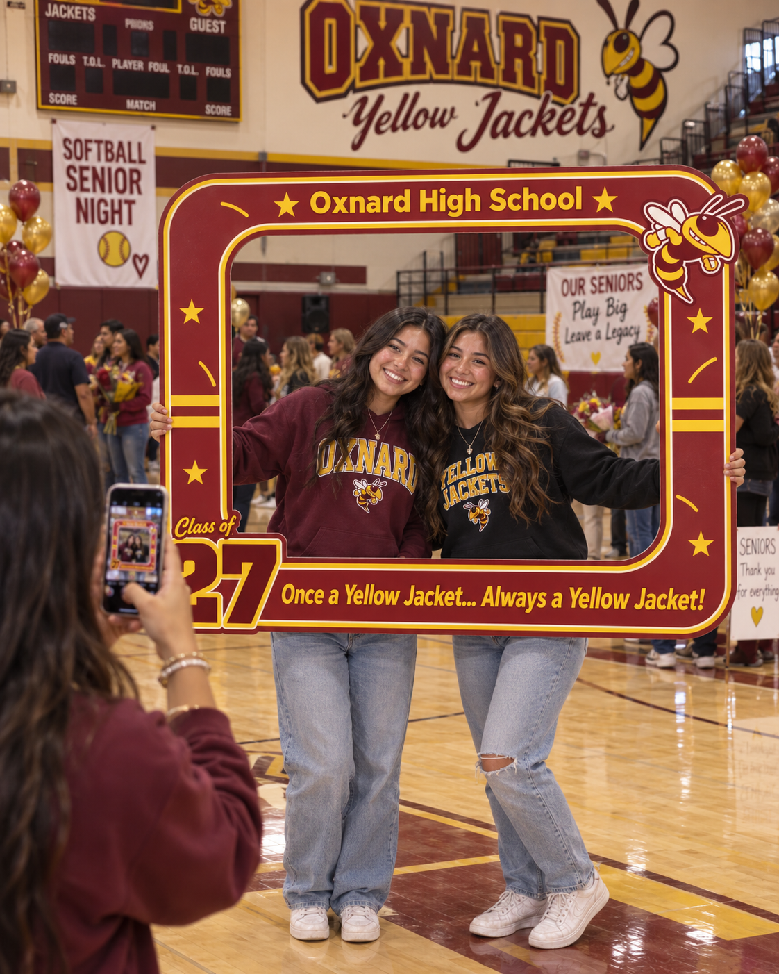 Two students holding a cardinal and gold Oxnard High School photo frame at Softball Senior Night