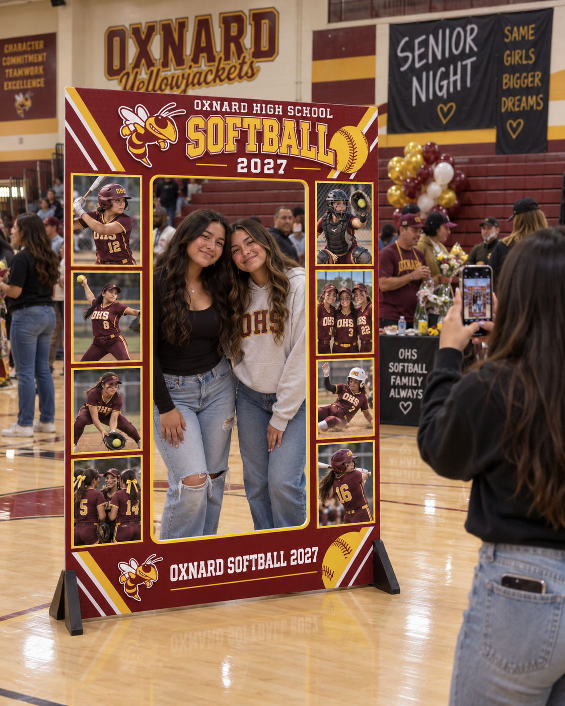 Two students posing in an Oxnard Softball 2027 tall photo frame at Senior Night