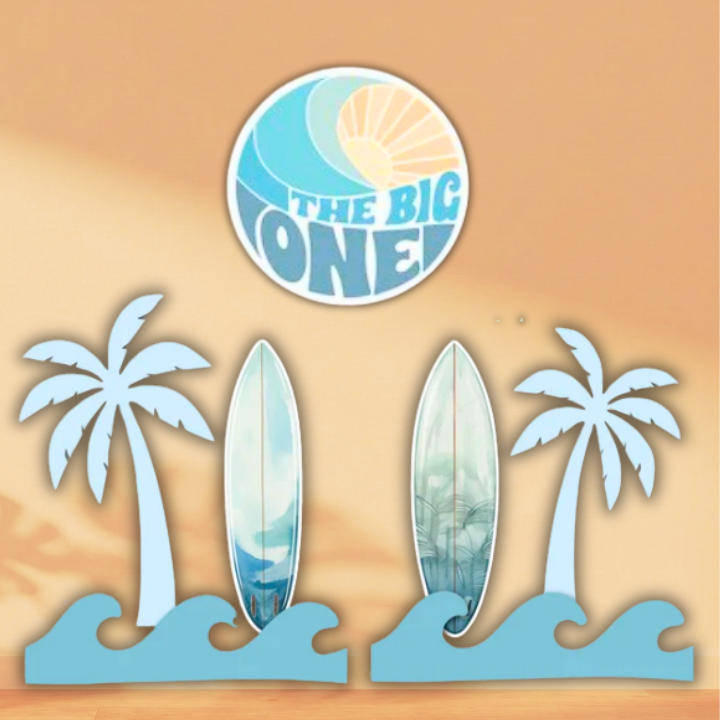 Surf-themed first birthday cutouts with two surfboards, palm trees, blue waves and a round The Big One sign.