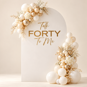 Ivory Talk Forty to Me arched birthday backdrop with gold lettering, cream and champagne balloon garlands and white flowers.