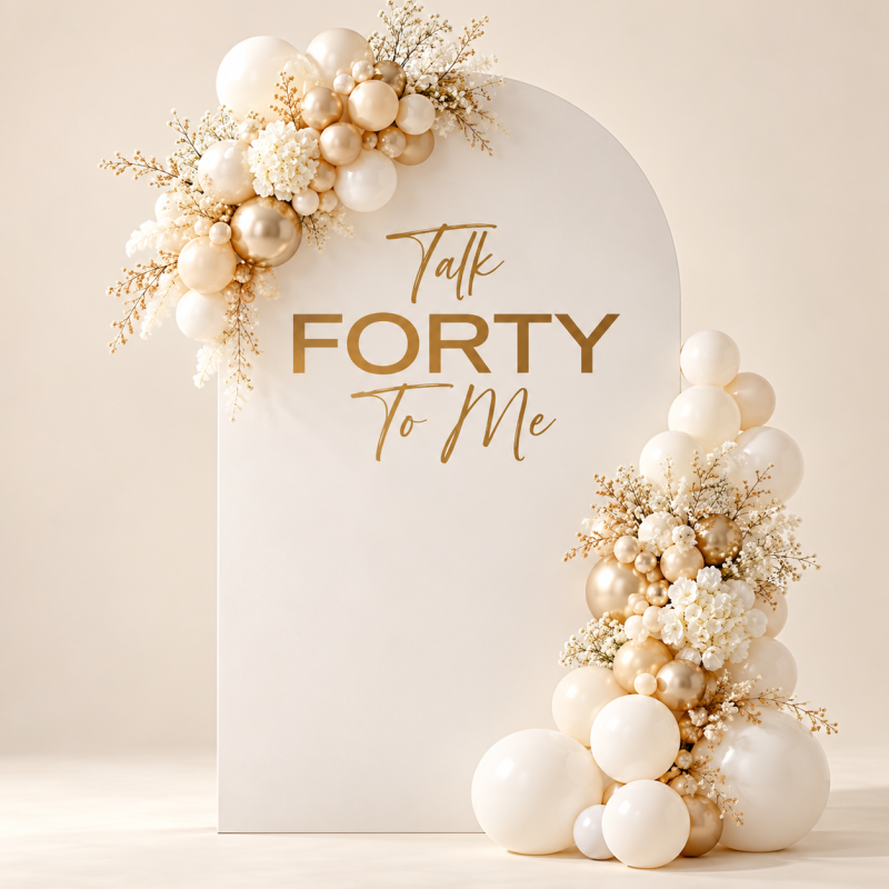 Ivory Talk Forty to Me arched birthday backdrop with gold lettering, cream and champagne balloon garlands and white flowers.